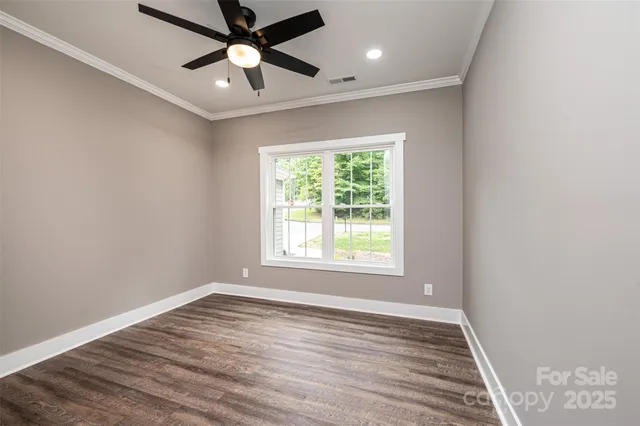 an empty room with wooden floor ceiling fan and windows
