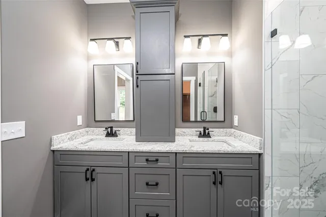 a bathroom with a granite countertop double vanity sink and a mirror