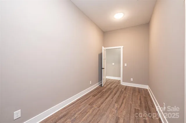 a view of an empty room with wooden floor and a ceiling fan