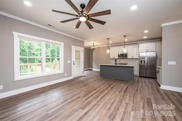 a view of a kitchen with a sink a refrigerator wooden floor and a window
