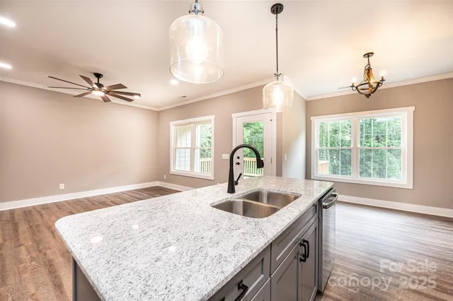 a kitchen with a sink a chandelier and wooden floor