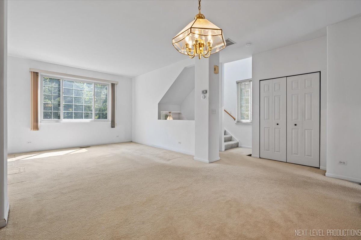 3382 Ravinia Circle, Unit 3382 Aurora, IL 60504 - Photo 9 of 33 en empty room with windows and chandelier