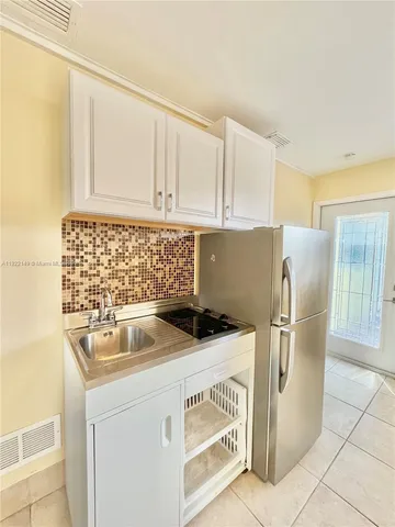 a kitchen with a sink a refrigerator and cabinets