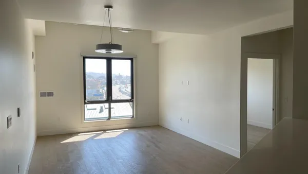 a view of an empty room with a window and wooden floor