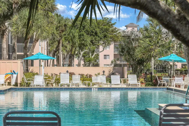 a view of swimming pool with a table and chairs under an umbrella
