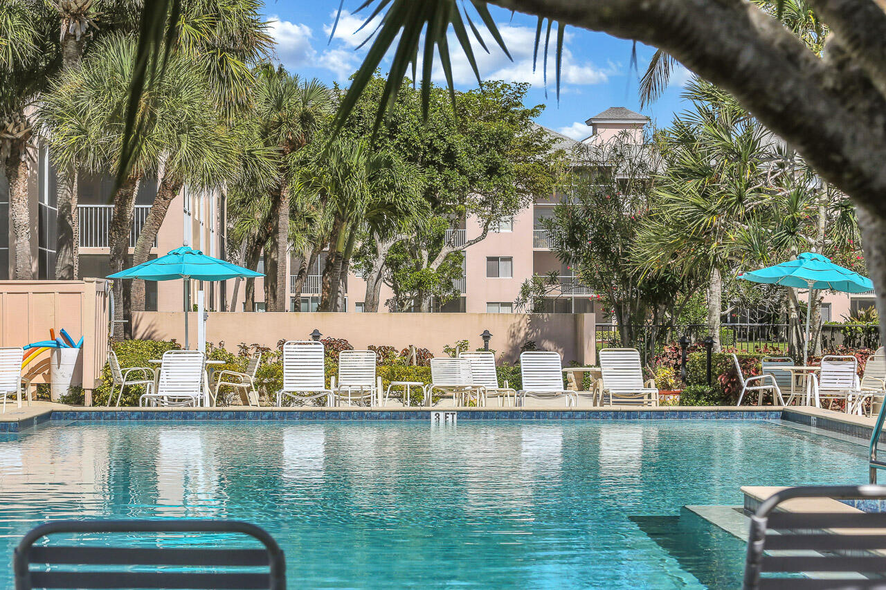 353 Highway 1, Unit A207 Jupiter, FL 33477 - Photo 23 of 28 a view of swimming pool with a table and chairs under an umbrella