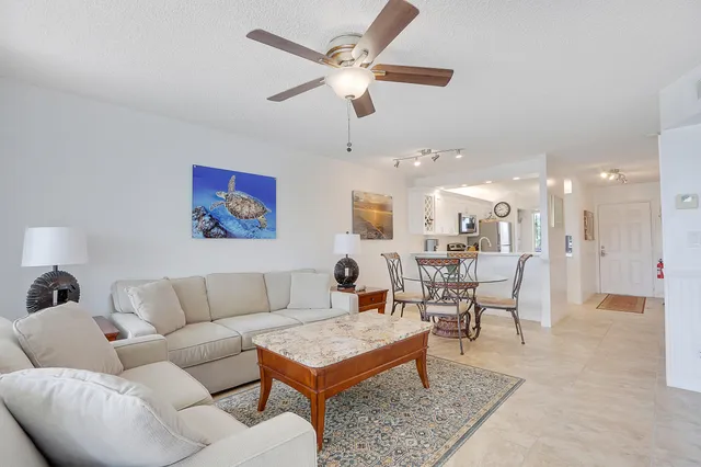 a living room with furniture kitchen view and a chandelier
