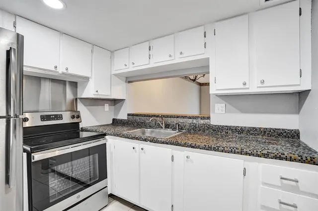 a kitchen with granite countertop white cabinets and a stove