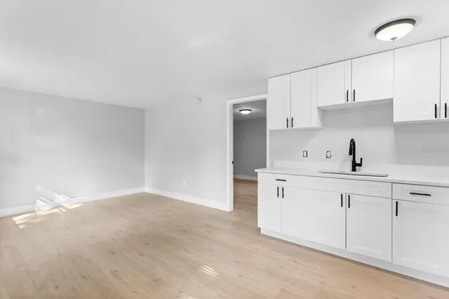 a kitchen with white cabinets and sink