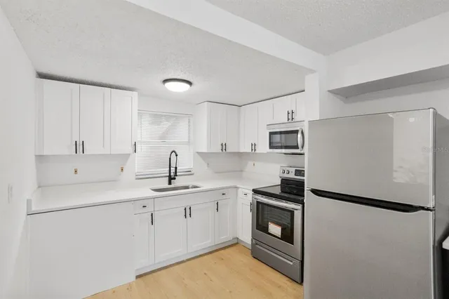 a kitchen with stainless steel appliances a refrigerator sink and white cabinets