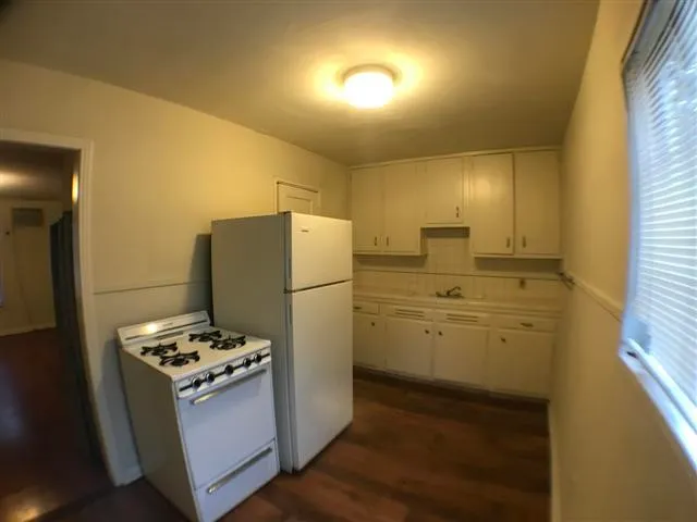 a kitchen that has a refrigerator a stove top oven a sink and dishwasher with wooden floor