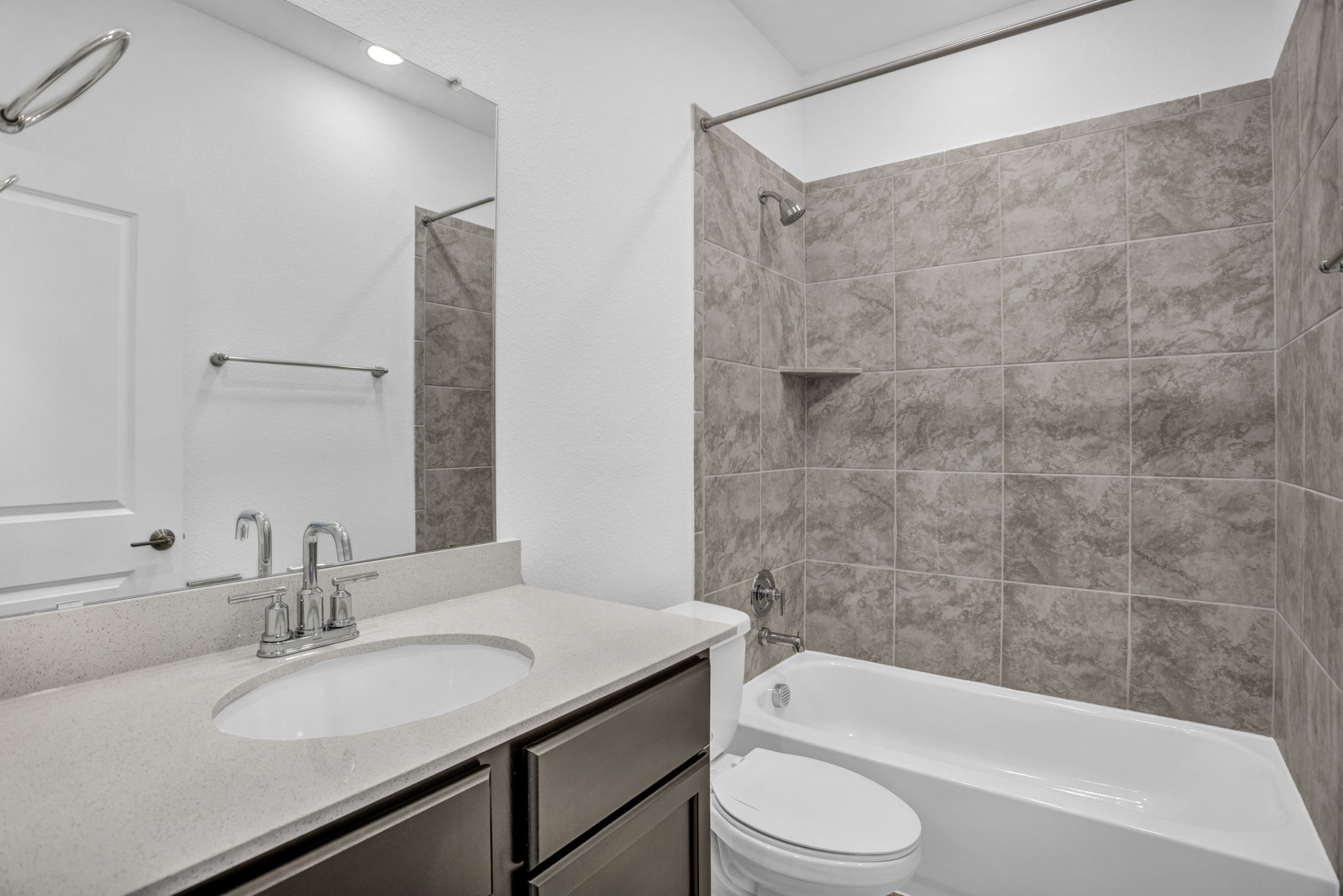 131 Adeline Road Hutto, TX 78634 - Photo 8 of 30 A well-appointed bathroom features a practical vanity with an undermount sink and a tiled shower-tub combination.