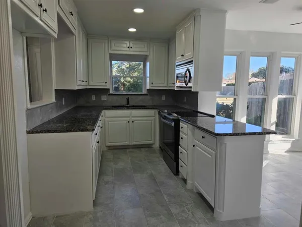 a kitchen with stainless steel appliances granite countertop a stove a sink and a microwave