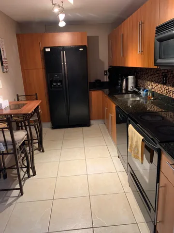 a kitchen with granite countertop a refrigerator and a stove top oven