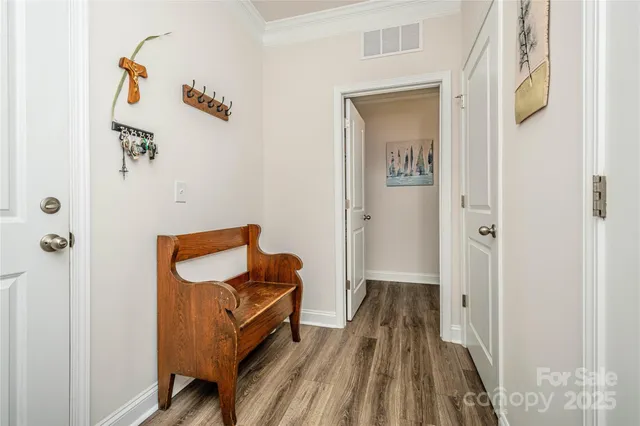 a view of a hallway with wooden floor and a bathroom