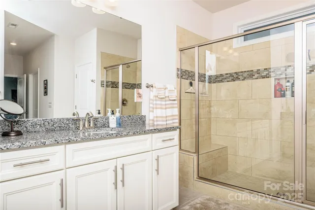 a bathroom with a granite countertop sink a mirror and shower