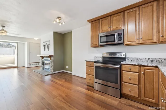 a kitchen with stainless steel appliances granite countertop a stove top oven a sink dishwasher and a microwave oven with wooden floor