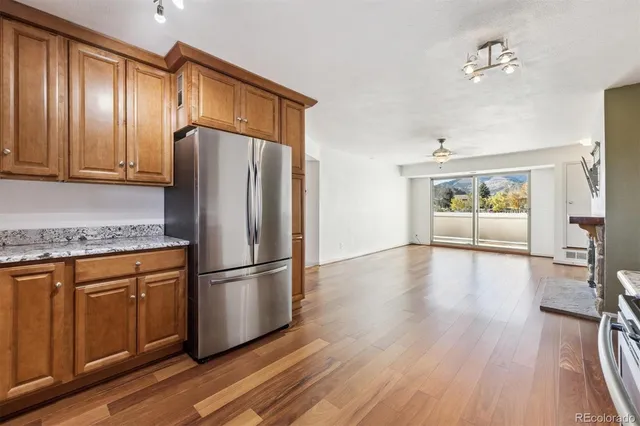a kitchen with stainless steel appliances granite countertop a refrigerator a stove and a wooden floors