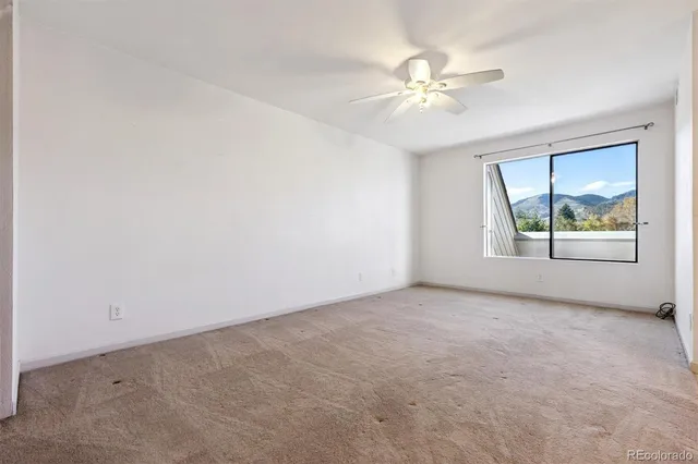 an empty room with a window and a ceiling fan