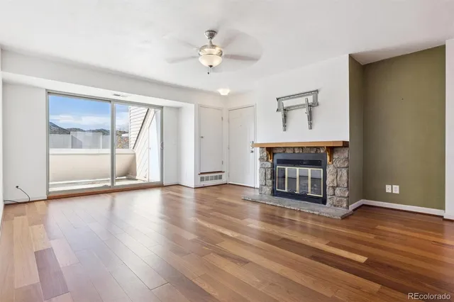a view of an empty room with wooden floor fireplace and a window
