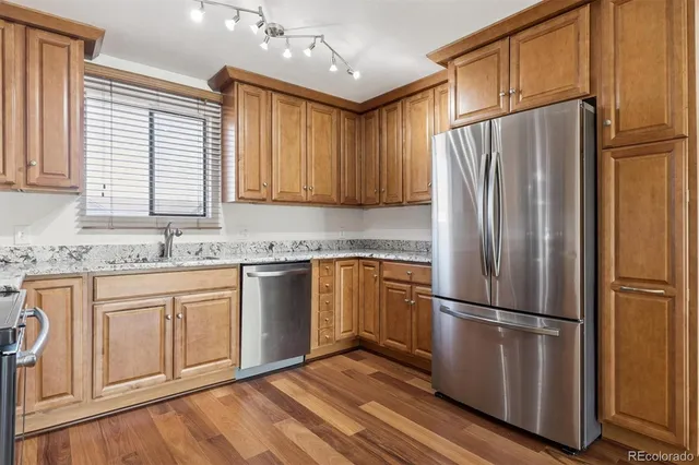 a kitchen with granite countertop stainless steel appliances a refrigerator cabinets and wooden floor