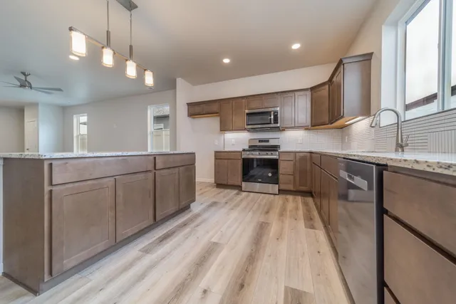 a kitchen with stainless steel appliances granite countertop a sink counter space cabinets and a large window