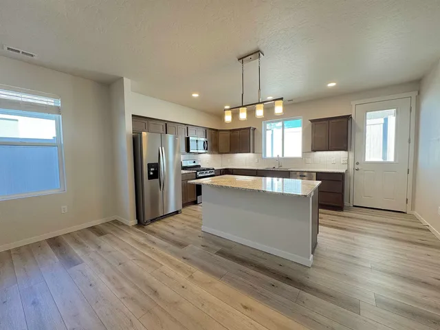 a large kitchen with a center island wooden floor stainless steel appliances and windows