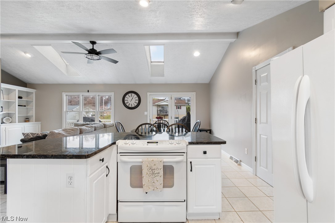 53330 High Ridge Road Bridgeport, OH 43912 - Photo 11 of 34 Kitchen featuring white cabinetry, white appliances, vaulted ceiling with skylight, light tile floors, and ceiling fan