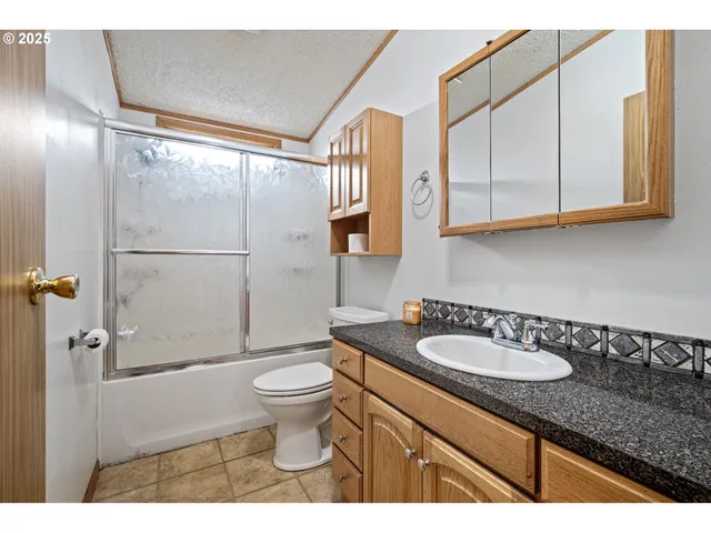 a bathroom with a granite countertop sink mirror vanity and toilet