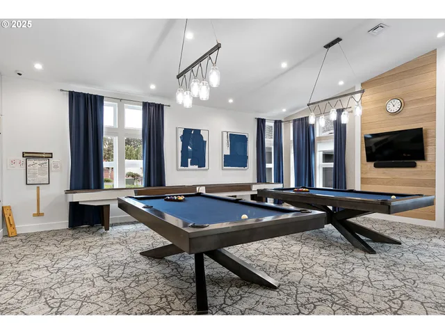 a room with furniture pool table flat screen tv and windows