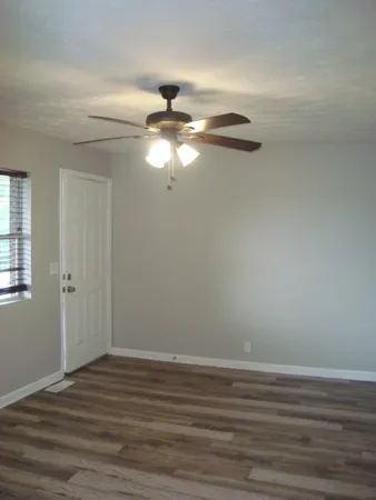 a view of a room with wooden floor fan and windows