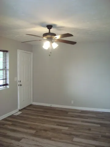 a view of a room with wooden floor fan and windows
