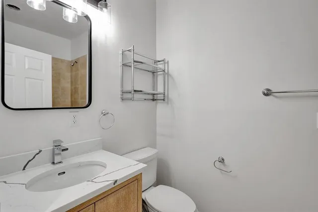 a bathroom with a sink vanity mirror and toilet