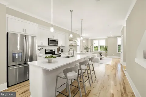 a kitchen with stainless steel appliances kitchen island a refrigerator a stove a microwave oven a sink with island and chairs