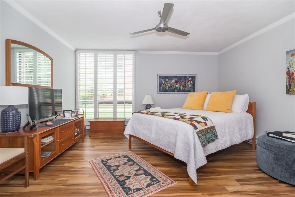 75 Grove Street, Unit 124 Wellesley, MA 02482 - Photo 13 of 22 a bedroom with a bed and wooden floor