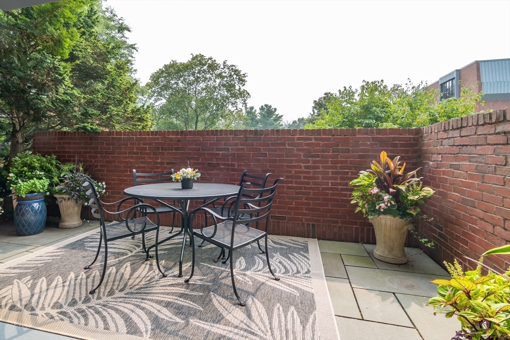 75 Grove Street, Unit 124 Wellesley, MA 02482 - Photo 17 of 22 a backyard of a house with table and chairs