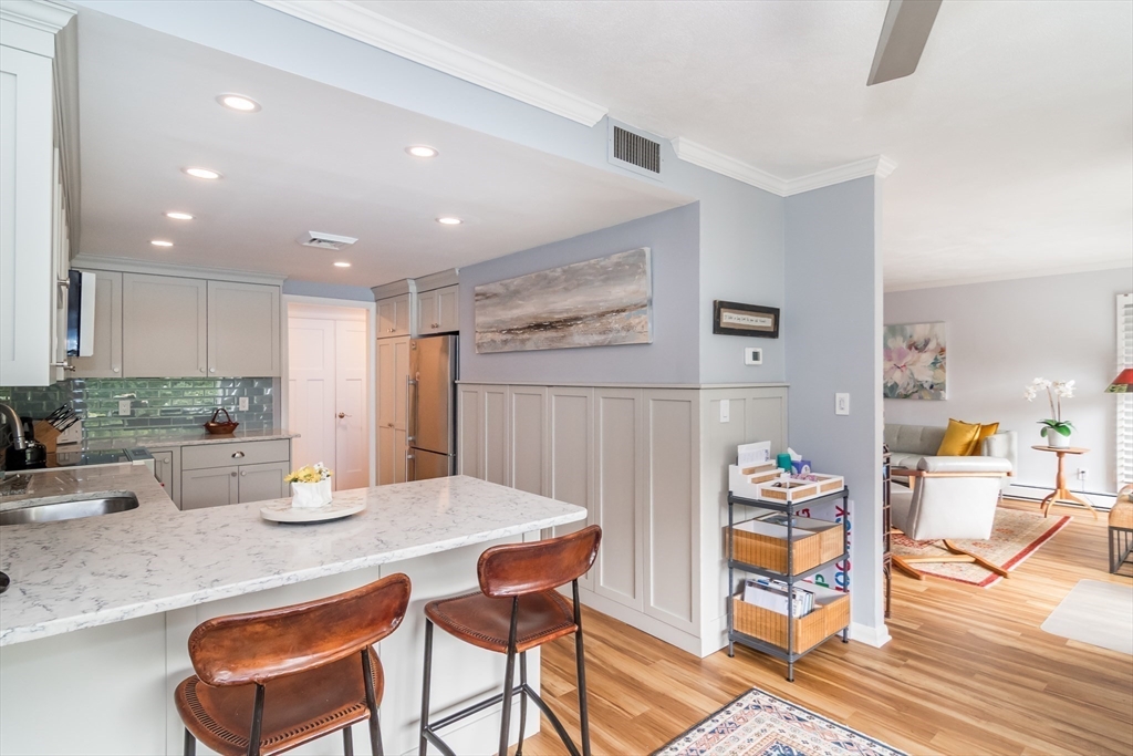 75 Grove Street, Unit 124 Wellesley, MA 02482 - Photo 6 of 22 a kitchen with stainless steel appliances granite countertop a table and chairs in it