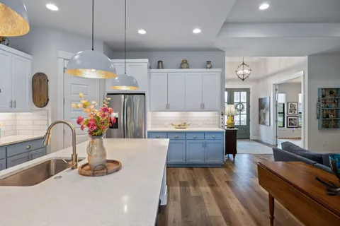 a large kitchen with kitchen island a stove a sink dishwasher and a dining table with wooden floor