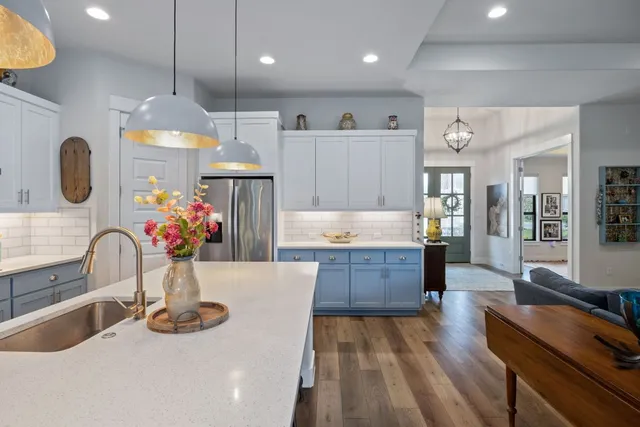 a large kitchen with kitchen island a stove a sink dishwasher and a dining table with wooden floor