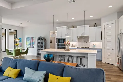 a living room with furniture kitchen view and a wooden floor