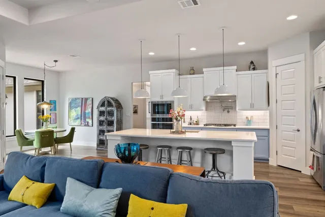 a living room with furniture kitchen view and a wooden floor