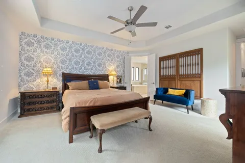 a bedroom with a bed a couch and a flat tv screen on dresser