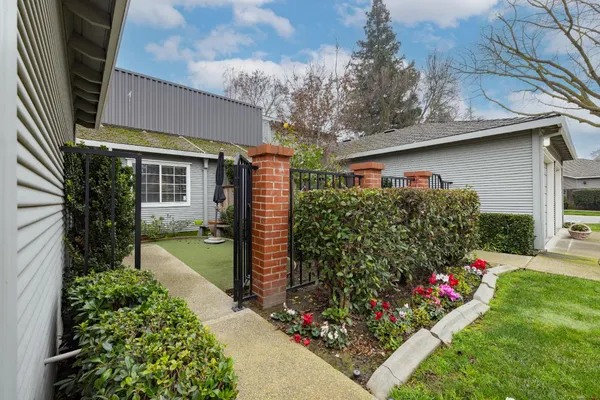 a backyard of a house with plants and large trees with wooden fence