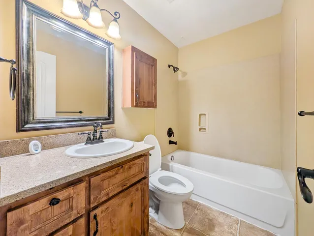 a bathroom with a granite countertop sink mirror vanity bathtub and a toilet