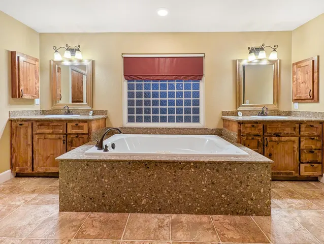 a spacious bathroom with a tub sink and mirror