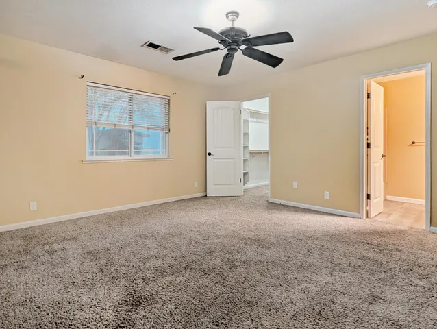 a view of a big room with windows and chandelier fan