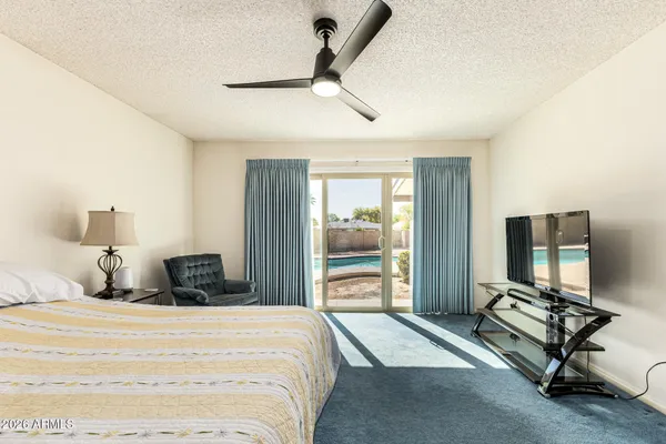 a bedroom with a bed a flat screen tv and a large window
