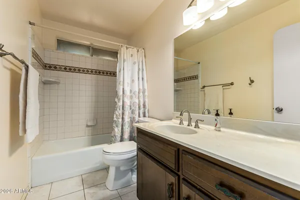a bathroom with a bathtub shower sink vanity mirror and toilet