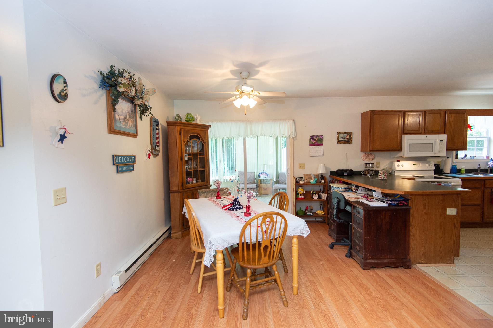 5834 Bell Creek Road Preston, MD 21655 - Photo 12 of 44 a kitchen with stainless steel appliances granite countertop a stove top oven a sink dishwasher and a dining table with wooden floor