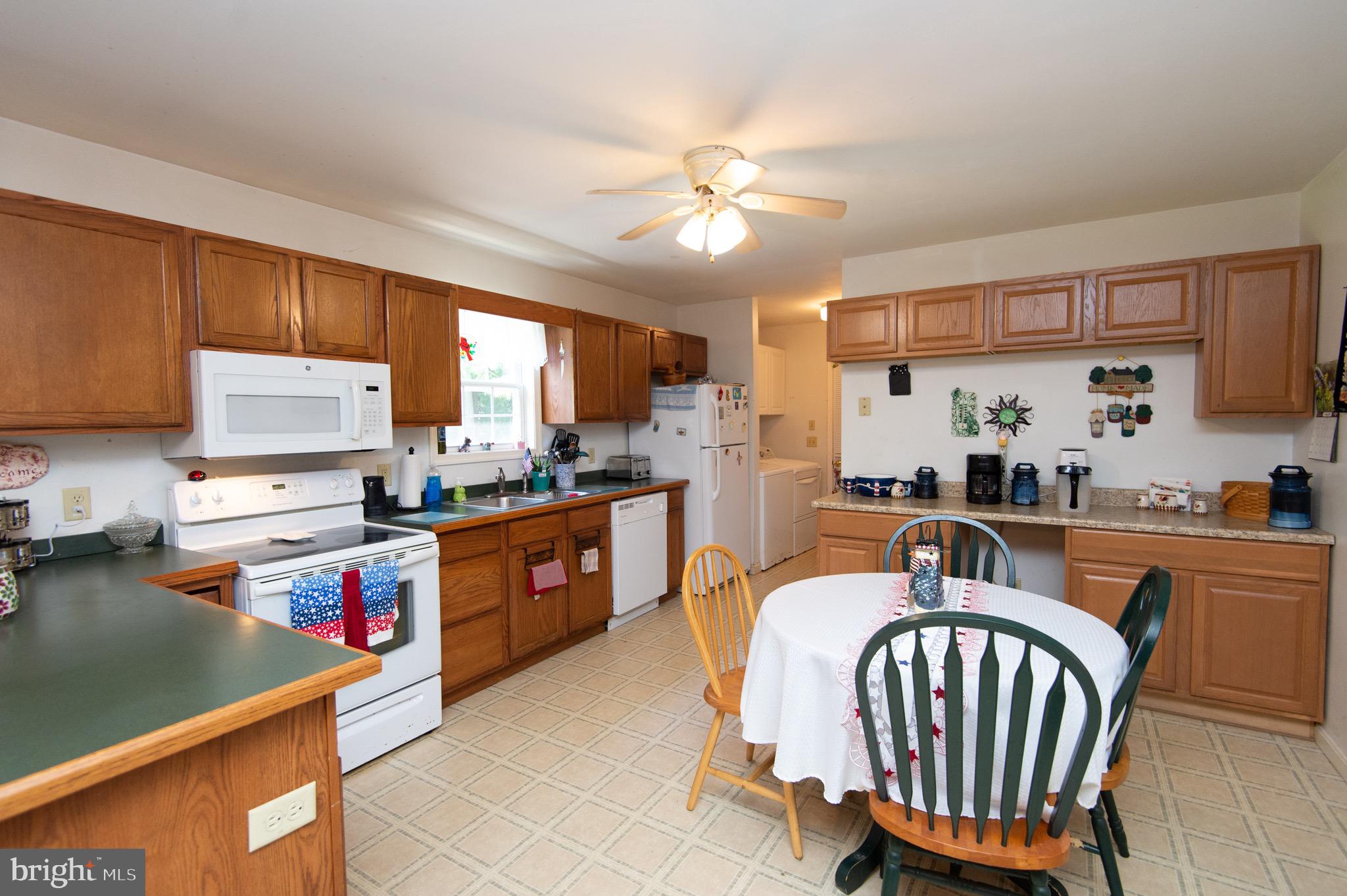5834 Bell Creek Road Preston, MD 21655 - Photo 16 of 44 a kitchen with stainless steel appliances granite countertop a sink dishwasher a stove a refrigerator with a dining table and chairs with wooden floor